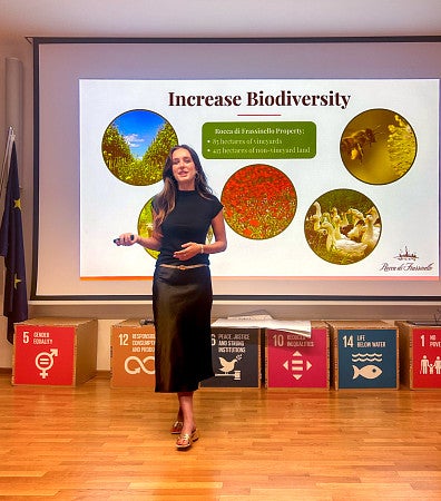 Charlie Hathaway gives a presentation in front of a digital screen titled "Increase Biodiversity"