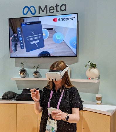 Kathleen Darby wears a VR headset in a expo booth for Meta