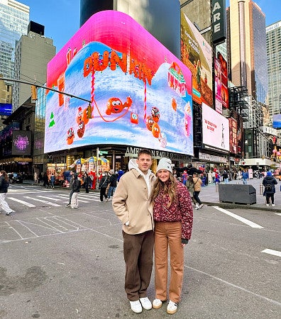 Jake Wilmink and a friend pose in front of a Dunkin' billboard in Times Square