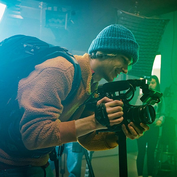 a person looks through the viewfinder of a video camera in a studio lit with green lights