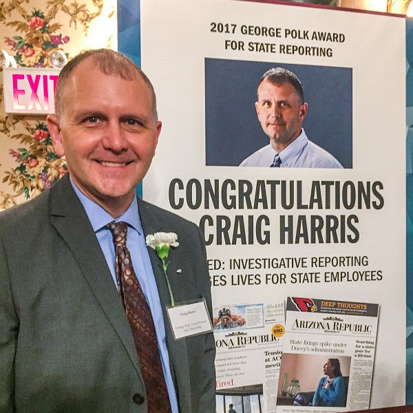 Craig Harris stands in front of a congratulatory sign for his 2017 George Polk Award