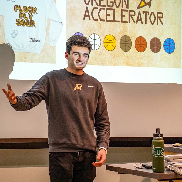 a student presents in front of a projector screen