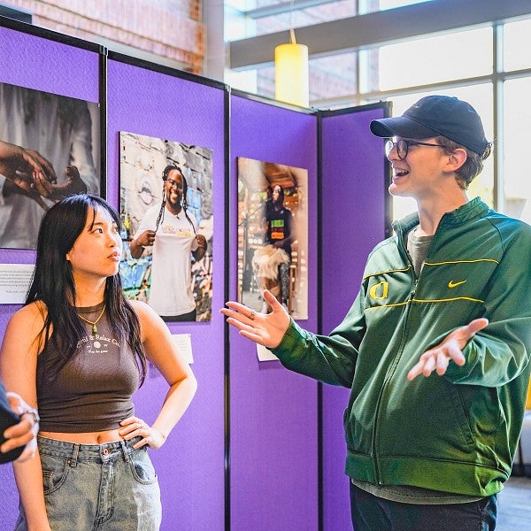 students chat in front of a purple wall displaying photos