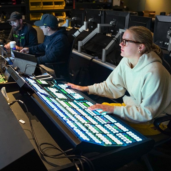 Sophie Fowler works at a control board in the foreground while her fellow students work in the background