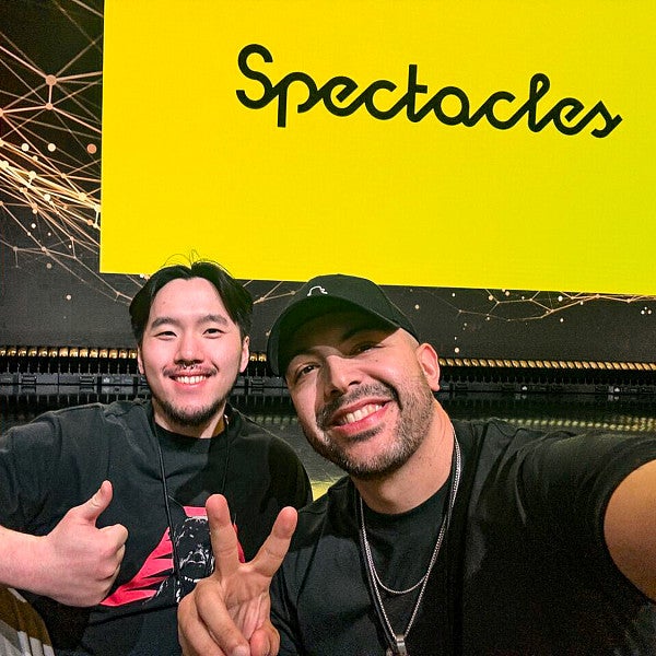 Isaac Wu and Danny Pimentel pose in front of a yellow screen with the Snap Spectacles logo