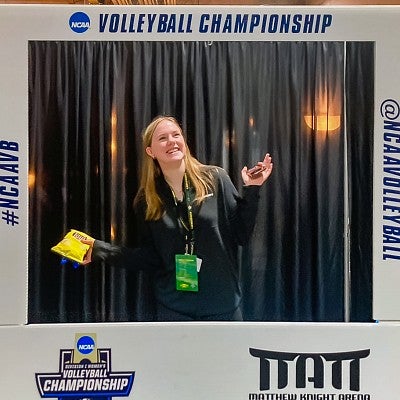 Sophie Fowler poses in the frame of a large cardboard cutout advertising the NCAA Volleyball Championship