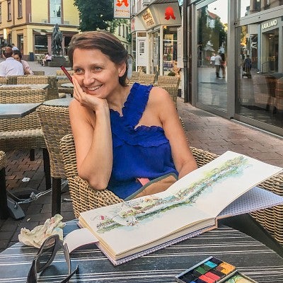 portrait of Rita Sabler drawing in an outdoor cafe