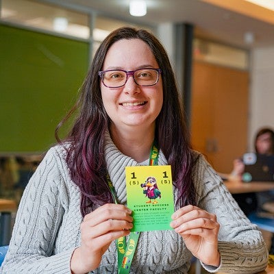Jessica Lovell holds a card with her likeness from SOJC Letters, a game created in a media studies production class