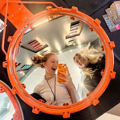 Maggie Troxell shoots a selfie in a mirror encased within a basketball hoop at the Gondola sports content marketing conference