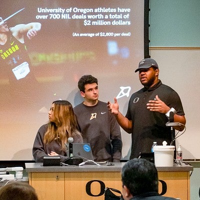 three students present in front of a digital screen