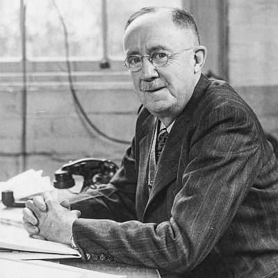 black and white portrait of Eric W. Allen sitting at his desk in the old journalism building