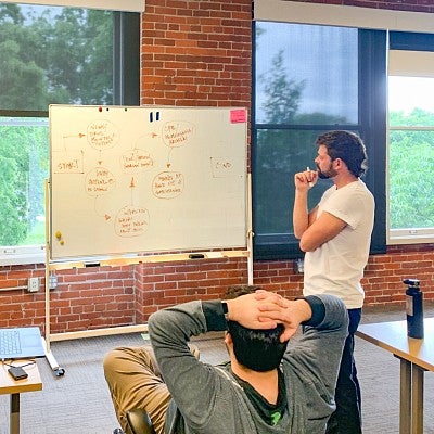 Two students review handwritten outline notes on a whiteboard