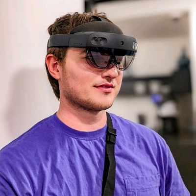 Alec Freudenstein wears a purple shirt and a Microsoft HoloLens 2 headset