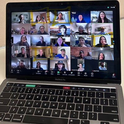 a laptop screen shows a Zoom meeting with dozens of people