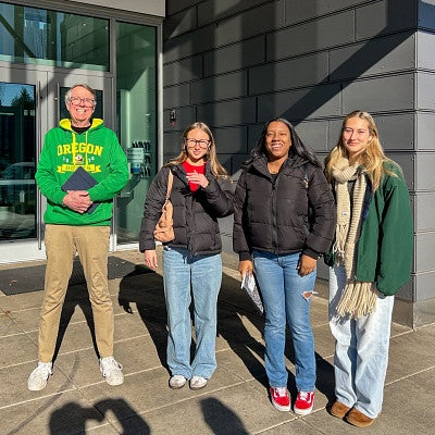 four people posing outside of a building