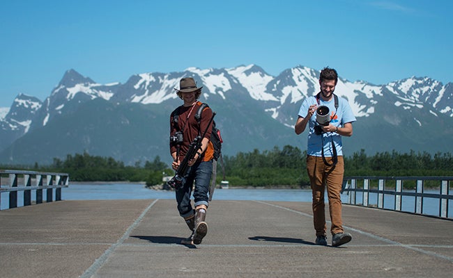 two male students with camera equipment with mountains in the background