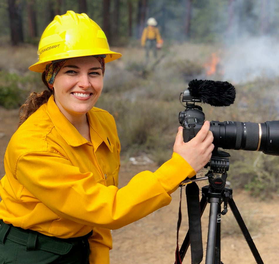 Journalism Master&#039;s student Miranda Daviduk in the field holding camera. 