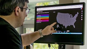Man pointing at a map of the United States on a computer monitor