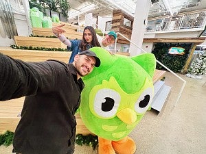 Zaria Parvez and a colleague pose for a selfie with the Duolingo owl mascot, Duo.