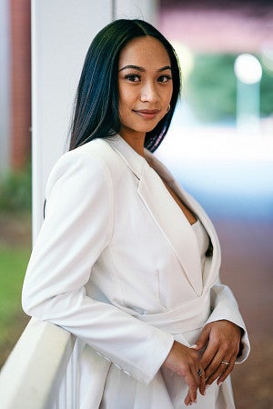 Madi Nguyen-Acosta poses for a portrait wearing a white suit