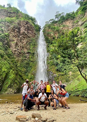 a group of SOJC students throw their Os in front of the Wli waterfall in Ghana