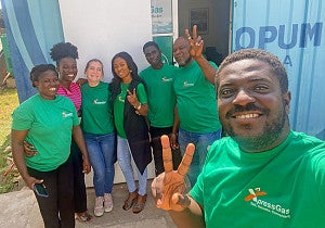 A group of people wearing green shirts smile and show peace signs