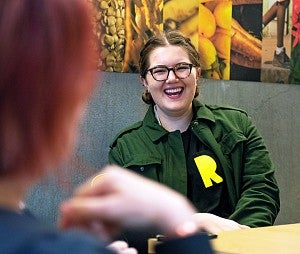 Discover graduate degrees a laughing female SOJC student sits in front of a colorful mural