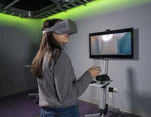 Student wears VR goggles while inside of the immersive media lab. 