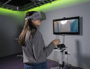 Student wears VR goggles while inside of the immersive media lab.