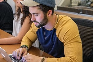 Student working on computer during class. Male student working on computer during class.