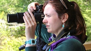 Woman looking through a camera viewfinder while taking a photo
