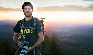 Justin Hartney standing on top of Spencer Butte holding a camera