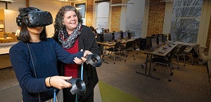 female student using wearable VR technology, assisted by female professor