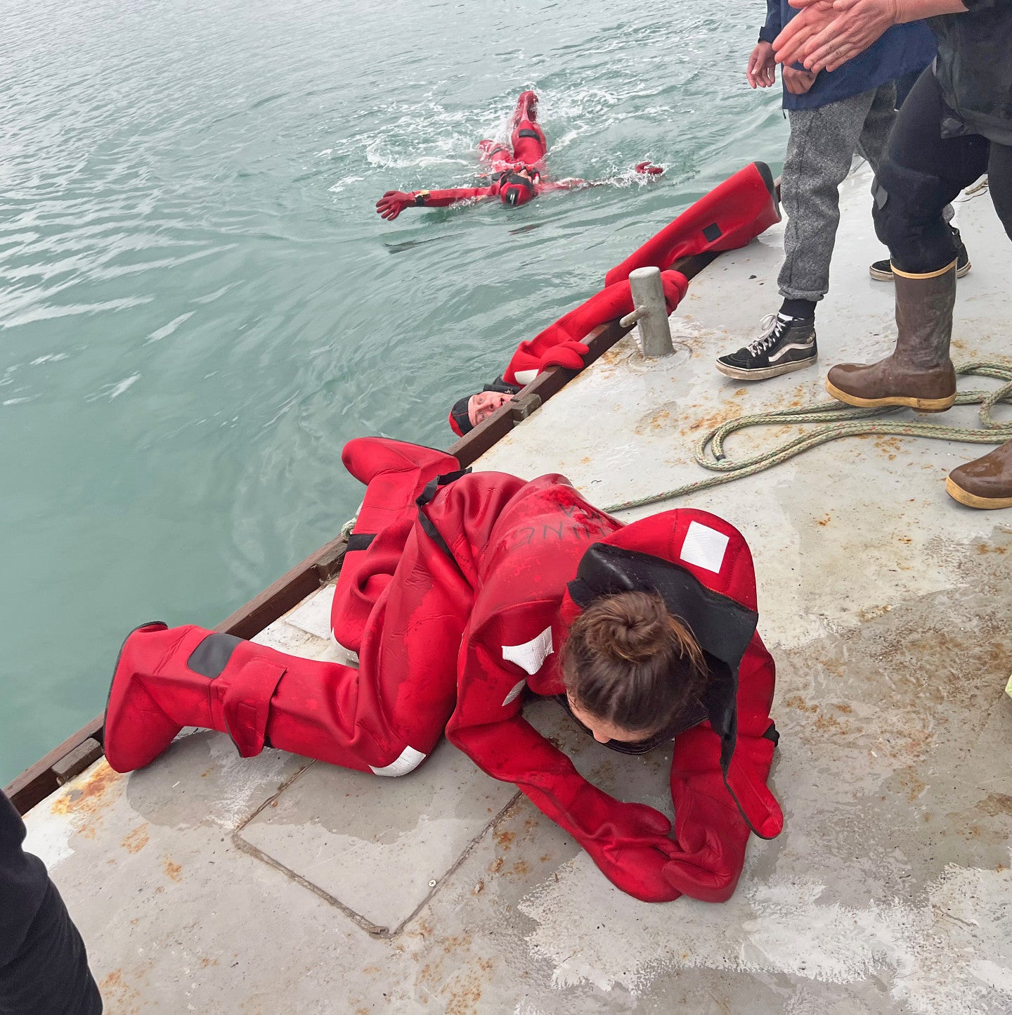 Charlie Boiler climbs out of the water wearing a red survival suit
