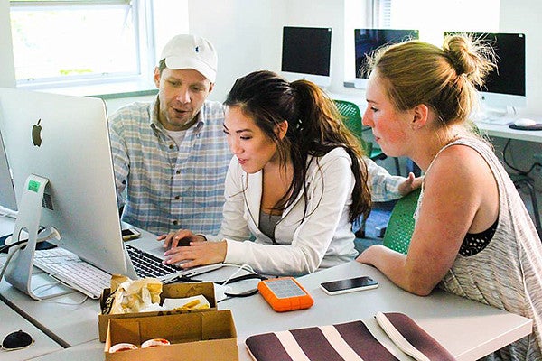 SOJC Instructor Steven Asbury and two students working on computer together