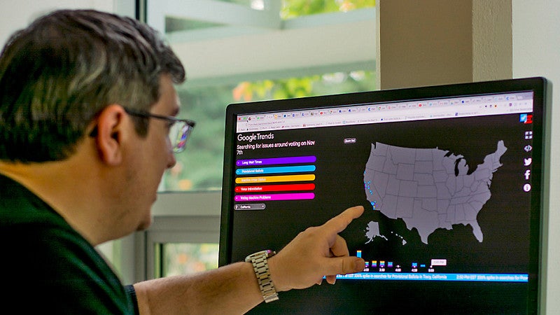 a person points at a computer screen showing a map of the US