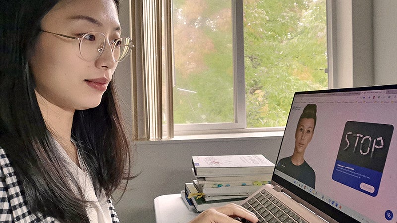Tingyou Zou works at a laptop showing a chatbot designed to assist in smoking cessation