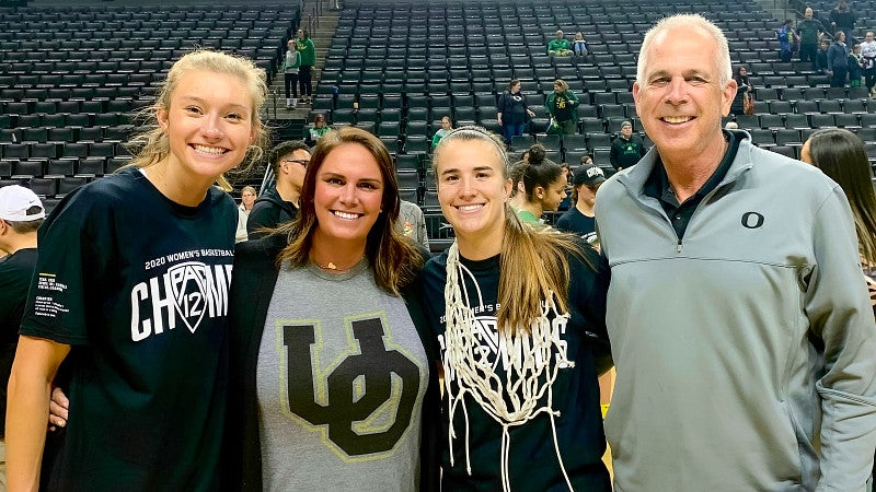 four people pose after a university of oregon women's basketball game