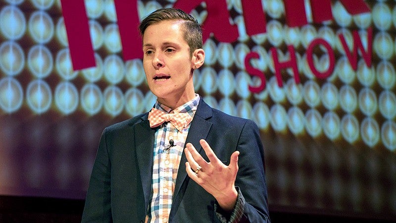 Dr. Erica Ciszek speaks in front of a screen while wearing a brown blazer. Dr. Erica Ciszek speaks in front of a screen while wearing a brown blazer.