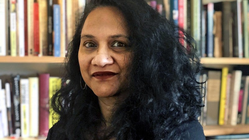 Kumi Silva faces the camera while sitting in front of a book shelf.