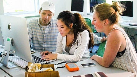 SOJC Instructor Steven Asbury and two students working on computer together