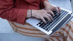 a person's hands typing on a laptop