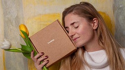 Woman poses with flowers and subscription box