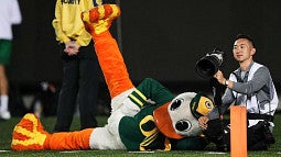 Ryan Kang on the sidelines of a football game with his camera, next to the University of Oregon Duck