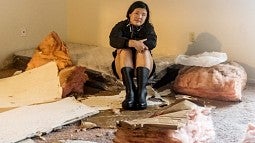Kezia Setyawan sits among fallen insulation and other debris in her partially demolished apartment after Hurricane Ida