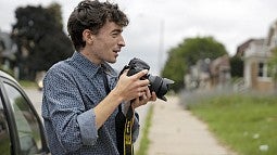 A young man holding a DSLR camera