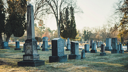 The morning light begins to hit a row of tombstones in a frost-covered graveyard (By Brett Sayles from Pexels). 
