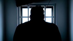 The silhouette of a prisoner looking out of a jail cell window (By Donald Tong from Pexels).
