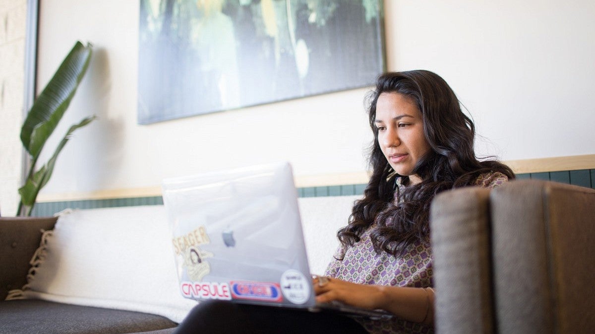 Jackie Gutierrez works on a laptop in an indoor setting