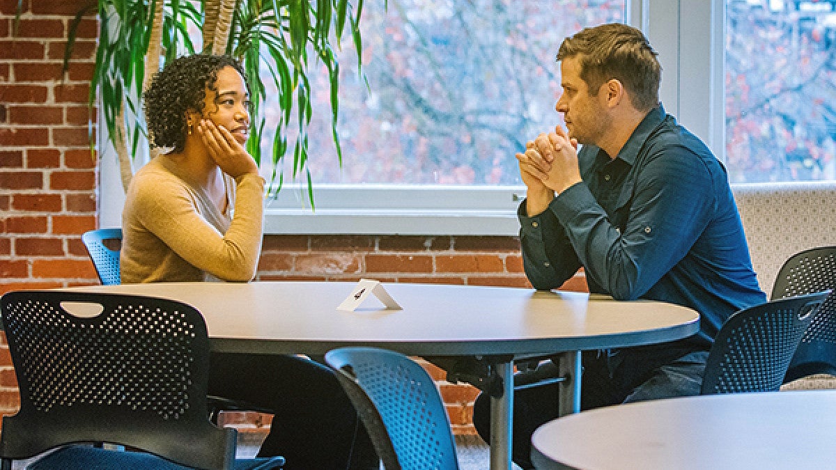 Two graduate students sitting at table Two students sitting together at round table